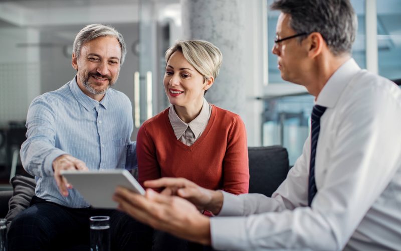 happy-mid-adult-couple-using-touchpad-with-their-financial-consultant-in-the-office-.jpg